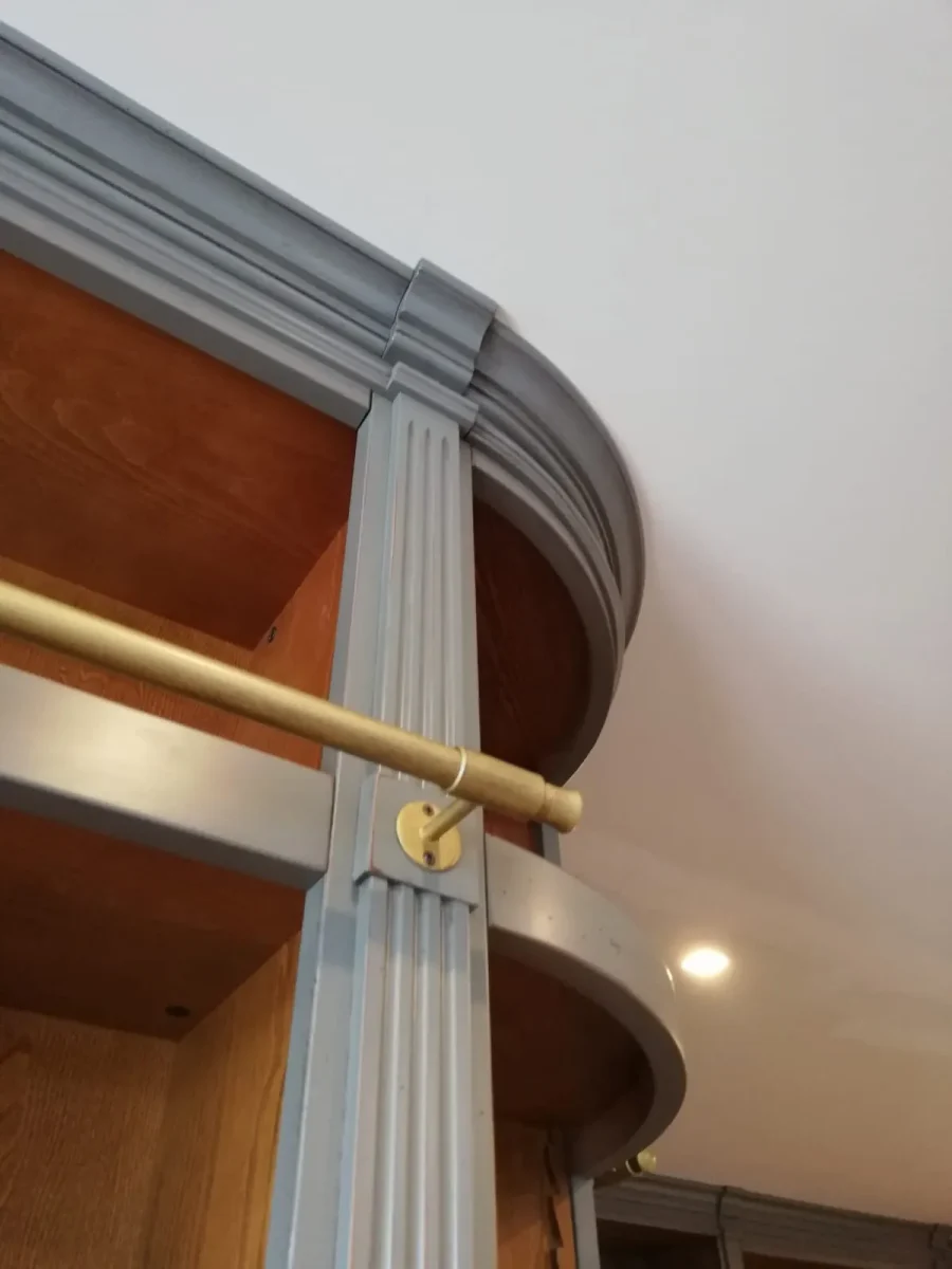 Dettaglio della guida in ottone della scala e della cornice curva in legno laccato grigio-azzurro
