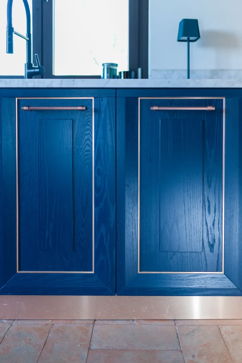 Ante a telaio in rovere laccato blu con filetto e maniglie in rame, sopra il pavimento in cotto